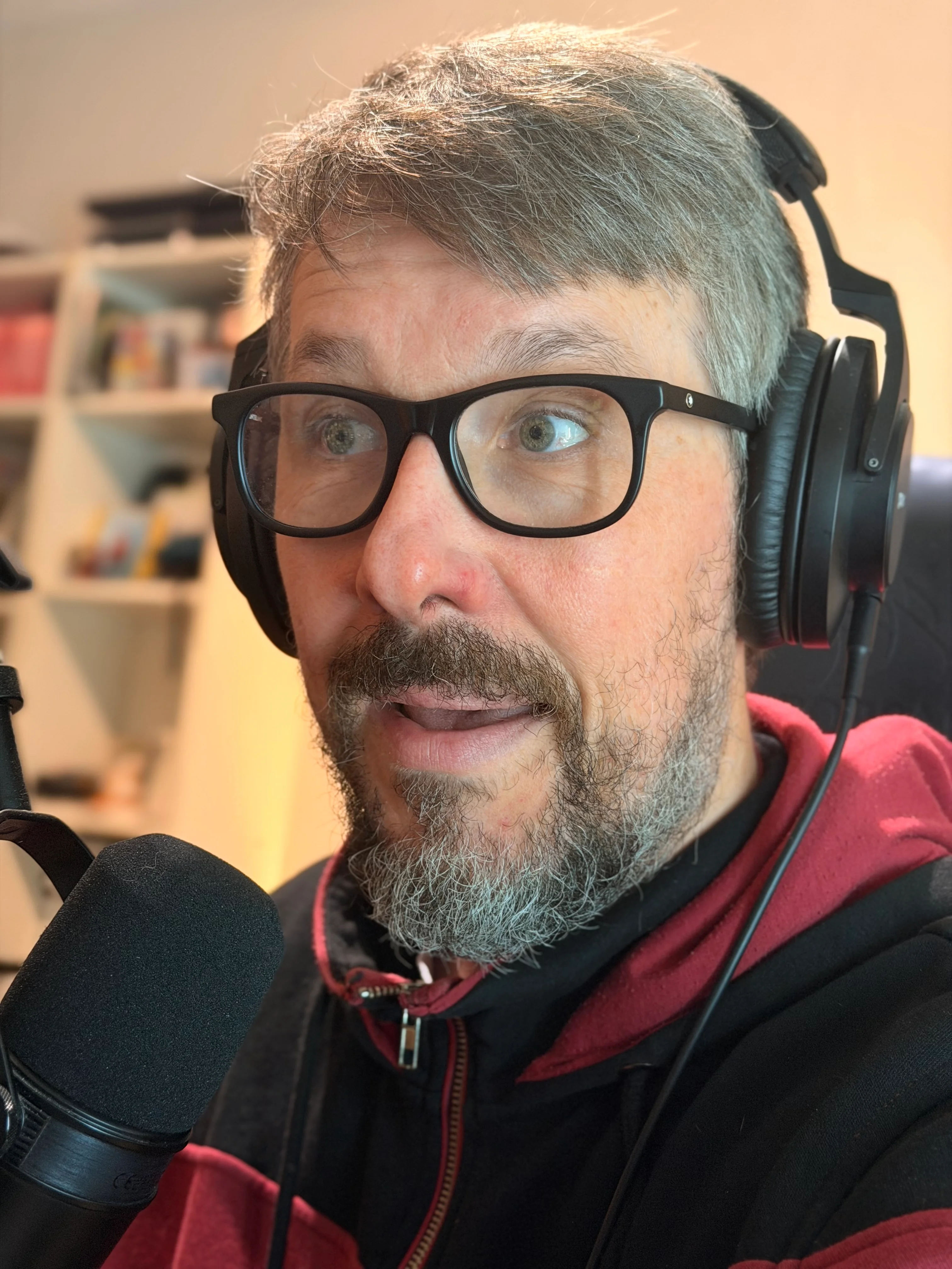 Déçu des Cartes au microphone, avec ses lunettes et son casque.
